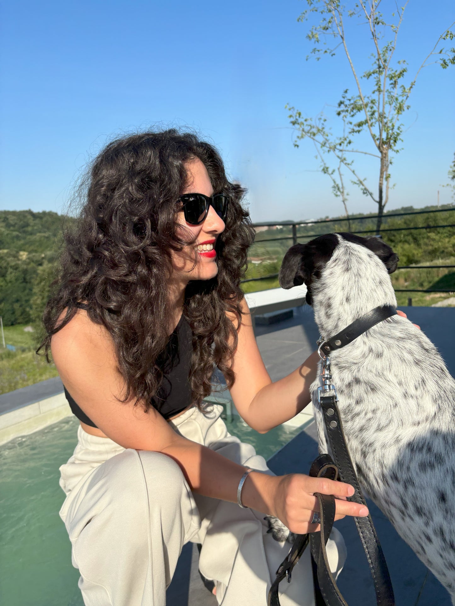 Luxury black leather collar and leash set with silver hardware, worn by a dog as the owner lovingly holds them, highlighting craftsmanship and elegance.
