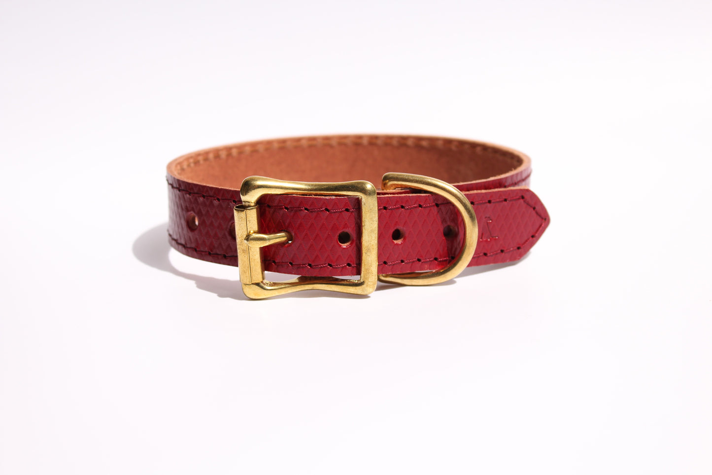 Luxurious red leather dog collar with golden brass hardware, showcasing refined elegance and premium craftsmanship.