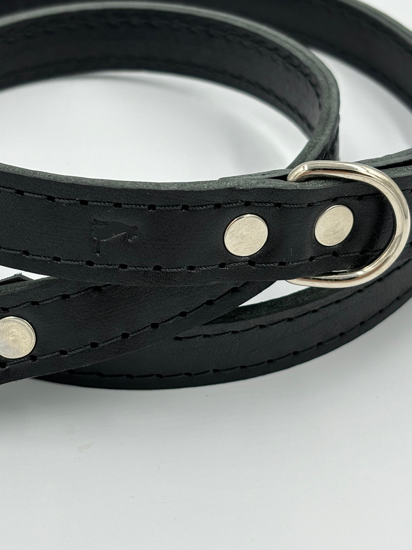Close-up of a high-quality black leather dog leash with silver hardware, demonstrating exceptional craftsmanship and timeless design.