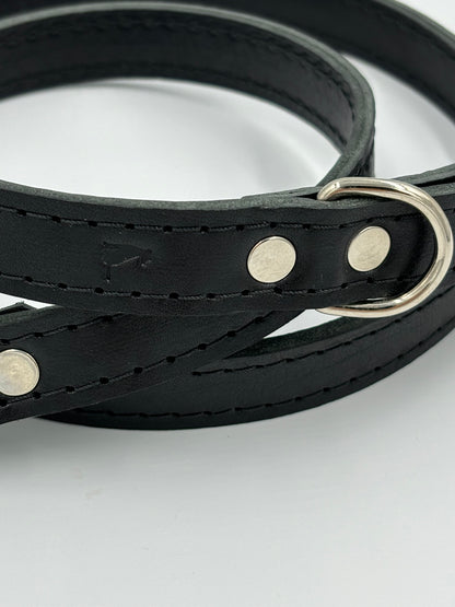 Close-up of a high-quality black leather dog leash with silver hardware, demonstrating exceptional craftsmanship and timeless design.