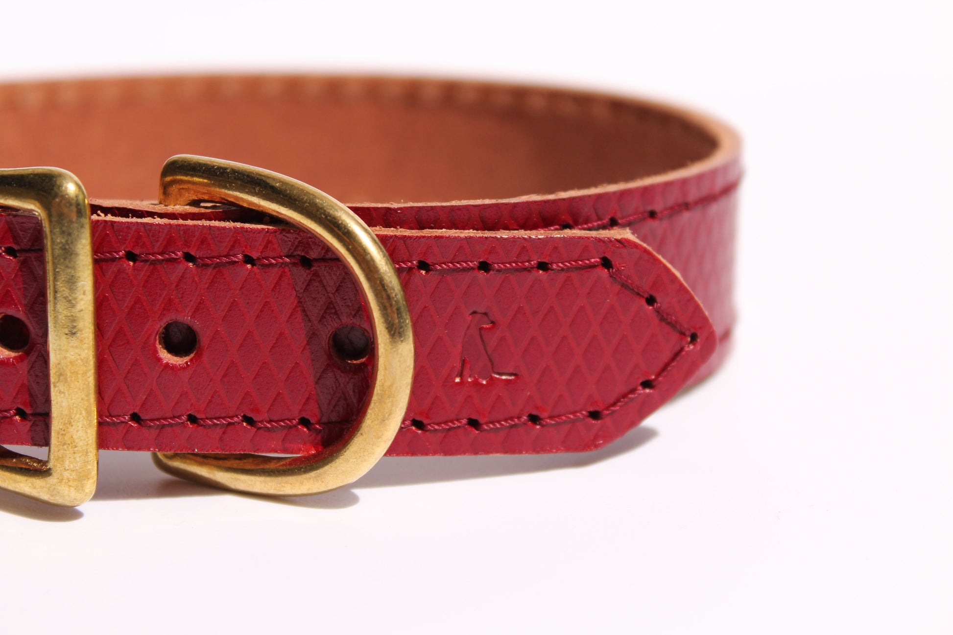 Close-up of luxury red leather dog collar with golden brass hardware, showcasing exquisite craftsmanship and sophisticated elegance.